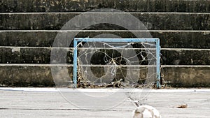 Pool boy kicking old football have laceration and net laceration small goal.