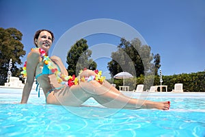 In pool in day-time woman sits in swimming suit