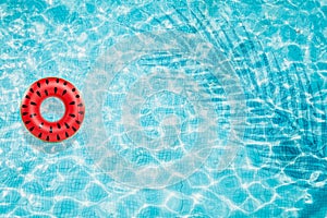 Pool float, ring floating in a refreshing blue swimming pool with palm tree leaf shadows in water