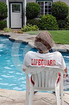 Giovane, seduto da una piscina privata con bagnino maglietta.