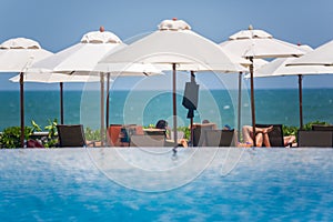 Pool and Ocean with beach chairs and umbrellas