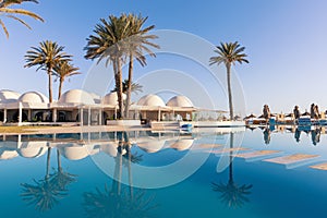 Pool and palm trees with traditional building with dome roof, Tunisia