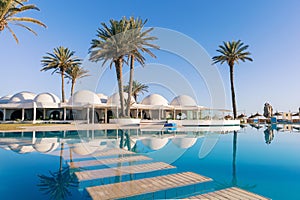 Pool and palm trees with traditional building with dome roof, Tunisia