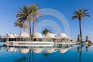 Pool and palm trees with traditional building with dome roof, Tunisia