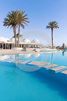 Pool and palm trees with traditional building with dome roof, Tunisia