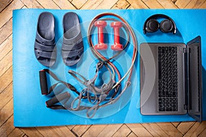 Pool slippers and a laptop. Fitness items and laptop. Rubber expanders and red dumbbells. Dumbbells and laptop.