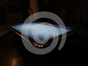 Pool table in hall with lit by lamps on a dark background