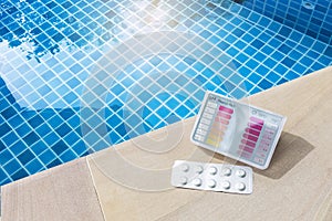 Pool tester test kit and tablets on swimming pool edge