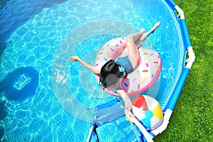 Pool time. Girl has fun in a summer metal frame pool