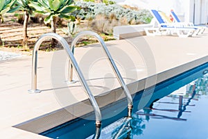 Pool with turquoise water and white sun loungers in a pine forest