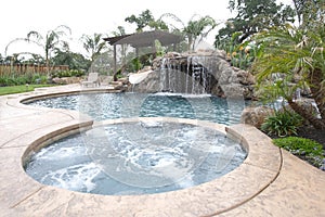 A pool with a waterfall in a luxury backyard