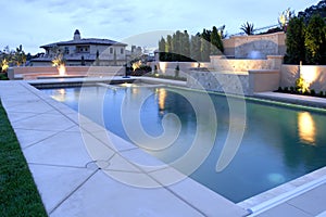 A pool with a waterfall in a luxury backyard