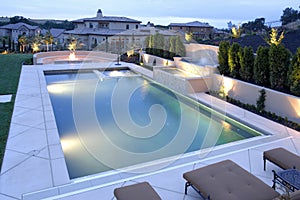 A pool with a waterfall in a luxury backyard