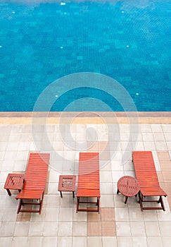 Poolside deckchairs alongside blue swimming pool