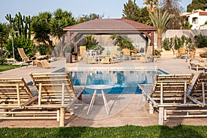 Poolside lounging area with bamboo chairs and table, pergola, tranquil mood for relaxation and social gatherings.