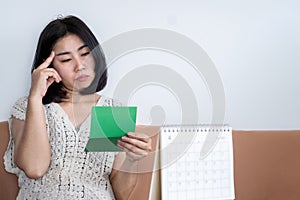 poor bankrupt asian woman checking her money in account book photo