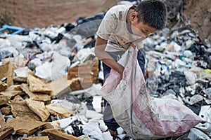 Poor boy collecting garbage in his sack to earn his livelihood, The concept of poor children and poverty photo
