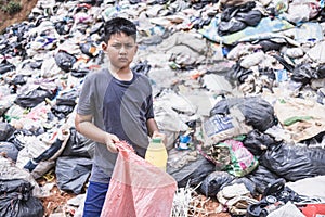 A poor boy collecting garbage waste from a landfill site in the outskirts . children work at these sites to earn their livelihood photo