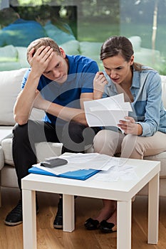 Poor couple reading unpaid bills