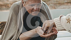 Poor elder homeless man receiving coins from woman