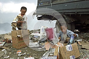 Poor Filipino boys gathering old paper on landfill