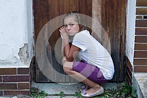 Poor girl sad in front of door