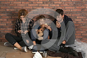 Poor homeless family sitting on floor