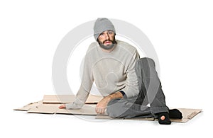 Poor homeless man sitting on cardboard, white