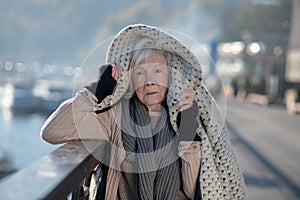 Poor homeless woman feeling very cold thus putting coat on head