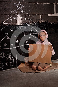 Poor kid at christmas time on the street with blank cardboard sign photo