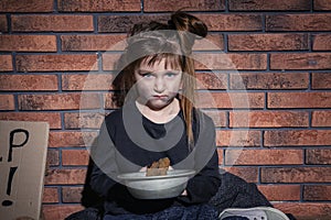 Poor little girl with bread against wall