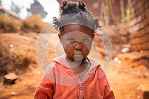 Poor little girl wearing dirty clothes in an African village, poverty and crisis concept