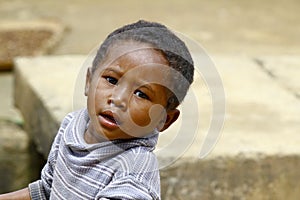 Poor malagasy boy carrying plastic water bucket