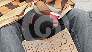 Poor man begging, shaking cup to draw attention, people giving money to homeless