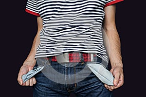 Poor man in jeans with empty pocket isolated on black