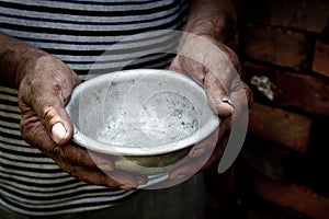 The poor old man`s hands hold an empty bowl. The concept of hunger or poverty. Selective focus. Poverty in retirement.Homeless. Al