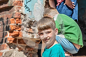 Poor orphans against the background of destroyed buildings, the concept of the life of street children. Staged photo