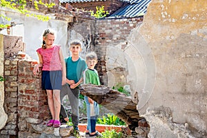 Poor orphans against the background of destroyed buildings, the concept of the life of street children. Staged photo