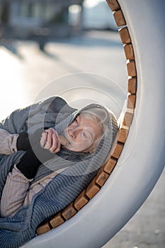 Poor pensioner eating cracker while lying on bench