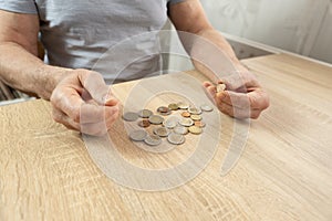 poor pensioner lays out euro cent coins on wooden table, counts meager cash money on table, illustrating harsh reality life in