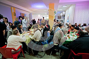 Poor people sit around tables with food at the Christmas charity dinner for the homeless