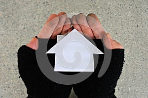 Poor person holding a house made out from Origami art of paper folding