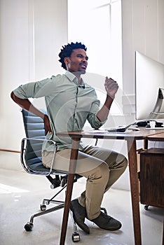 Poor posture can lead to unbearable pain. a young designer suffering from back pain while working at his desk in an