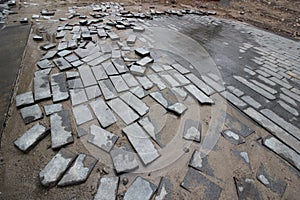 Poor quality paving stones, road blurred, road repair close up.