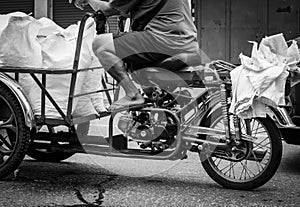 Poor senior man driving a motorbike, sending ice bag to a restaurant. Elderly people work after retirement. Retirement money