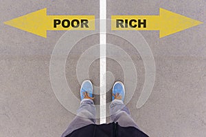 Poor vs Rich text arrows on asphalt ground, feet and shoes on fl