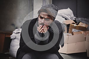 Poor young man sitting near garbage at dump