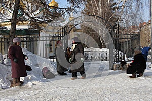 Russia, Novosibirsk, February 23, 2019: poorly dressed unemployed women pensioners beggars begging and money near the Church alms