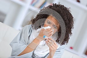 Poorly woman blowing nose and looking at thermometer