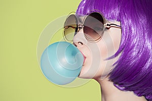 Pop art woman portrait wearing purple wig. Blow a blue bubble